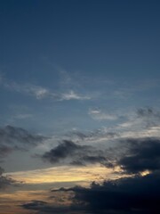 Obraz premium Dramatic Evening Sky with Dark Clouds and Soft Sunset Light. Atmospheric blue sky with storm clouds and glowing horizon at dusk, natural weather background with copy space.