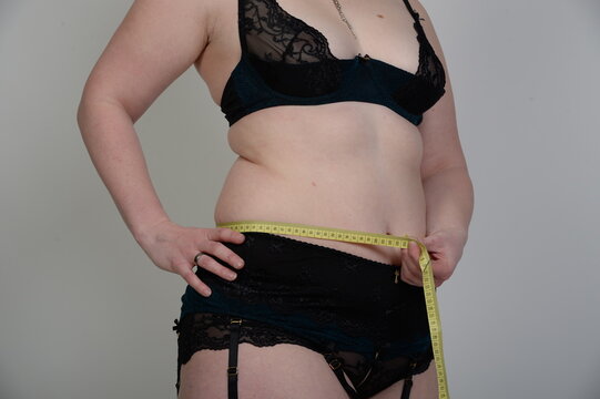 &Uuml;bergewichtige Frau misst ihren Taillenumfang mit einem Ma&szlig;band. Konzept f&uuml;r Abnehmen, Gewichtsreduktion, Di&auml;t, Fitness, Gesundheit und K&ouml;rperbewusstsein. Echtfoto.
