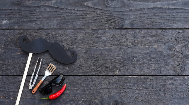 Grilling accessories with mustache prop for funny dad jokes on wood table