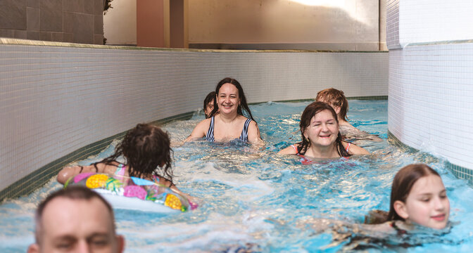 Happy family with children relaxing and swimming down a lazy river stream at an indoor water park