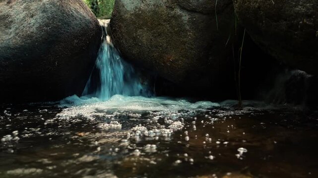 Small Waterfall Flowing Between Large Rocks in Rocky Stream