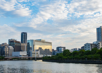 Naklejka premium 夕暮れ時の美しい雲とガラスビルに反射する夕日と川の景色