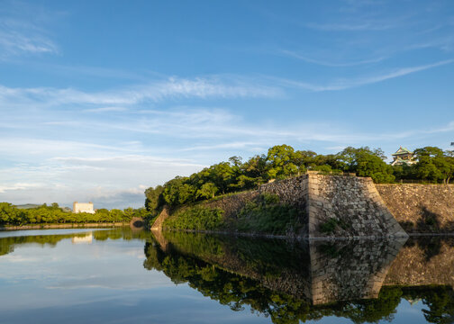 大阪城の石垣と外堀に映る美しい新緑と青空の水鏡風景