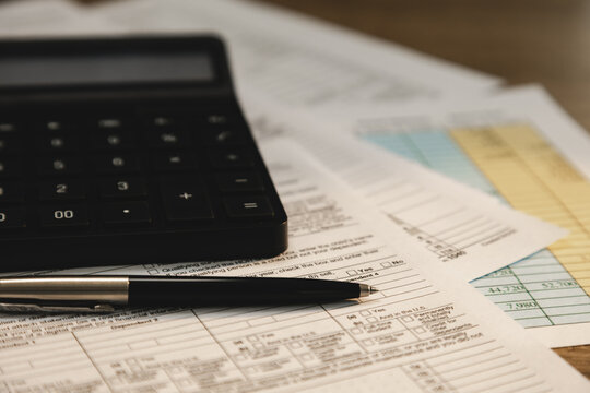 Calculator and pen placed on tax forms and financial statement documents for real estate information, accounting analysis, tax calculation, and financial reporting workflow.