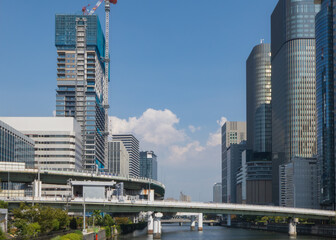 Obraz premium 青空が広がる昼下がりの大阪中之島高層ビル群と川を渡る高速道路