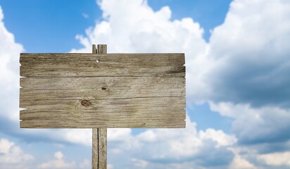 Fototapeta premium Blank wooden sign standing outdoors against a bright blue sky with white clouds background