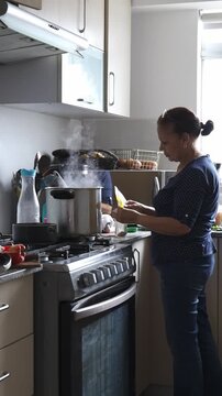 Hispanic woman hands chopping fresh green parsley on kitchen counter board