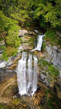 Aerial view of The Herisson waterfalls cascading down steep rocky cliffs surrounded by lush green forest in Menetrux-en-Joux, Bourgogne-Franche-Comte, France.