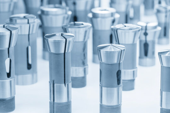 Close-up of a group of high-precision steel collet chucks and tool holders in a blue-toned scene.