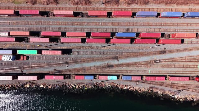 Hovering over the vibrant Halifax waterfront, observe the bustling railway where colorful cargo wagons are lined up for efficient shipping and logistics operations