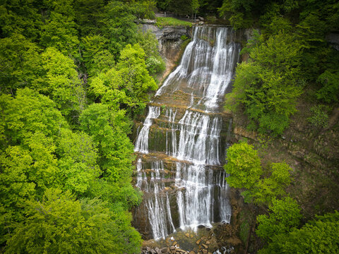 Aerial view of the Herisson waterfalls cascading down rocky tiers surrounded by dense green forest in Menetrux-en-Joux, Bourgogne-Franche-Comte, France.