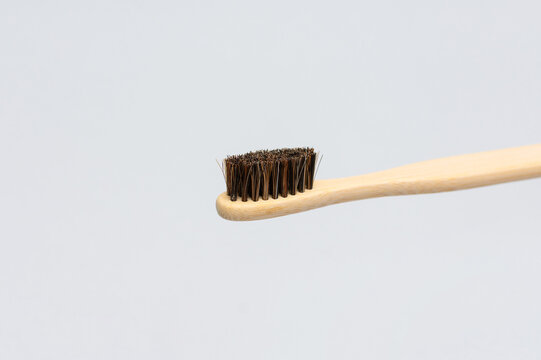 Close up of bamboo toothbrush bristles entering from right on gray background