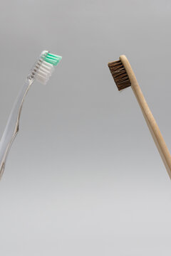 Plastic and bamboo toothbrushes facing each other in confrontation concept vertical composition