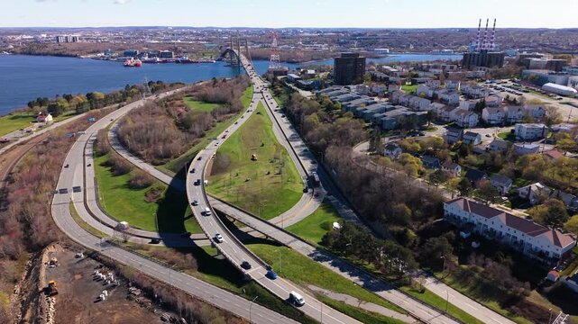 This aerial perspective captures a bustling traffic intersection near a bridge in Halifax, Nova Scotia, highlighting the dynamic city life and stunning waterfront