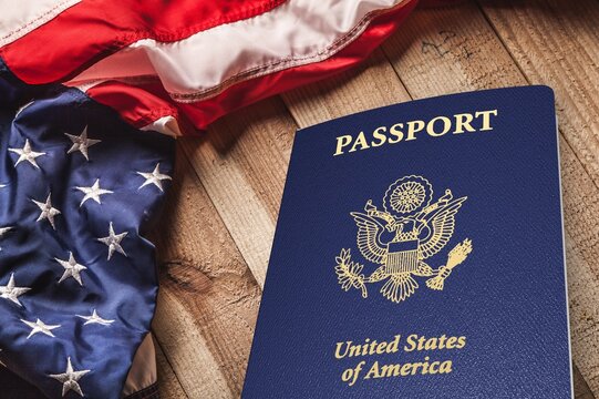 United States passport and American flag on a wooden table for travel and immigration concept
