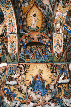 Interior view of Rila Monastery main church, showcasing the massive golden carved wooden iconostasis with sacred orthodox icons and colorful biblical wall frescoes, UNESCO site, Bulgaria