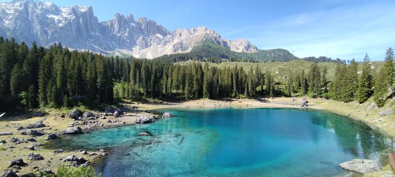 Splendido Lago di Carezza con acque turchesi e il massiccio del Latemar riflesso nelle Dolomiti