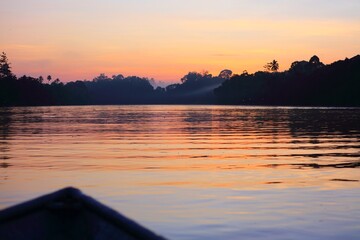 Obraz premium Sunrise and rainforest on Kinabatangan River in Sukau in Sandakan Division, in northeastern Sabah, Malaysia.