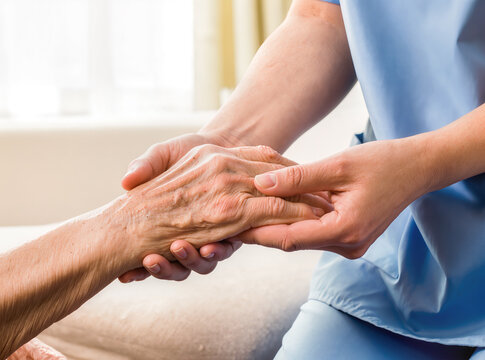 Close up of caregiver holding elderly patient's hand in healthcare setting