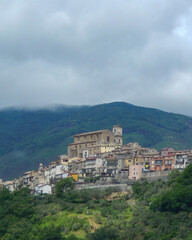 Fototapeta premium Historic village on a hill with buildings and mountains in the background under cloudy sky