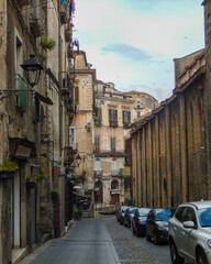 Obraz premium Narrow street with buildings and parked cars in an old city during cloudy weather in the late afternoon