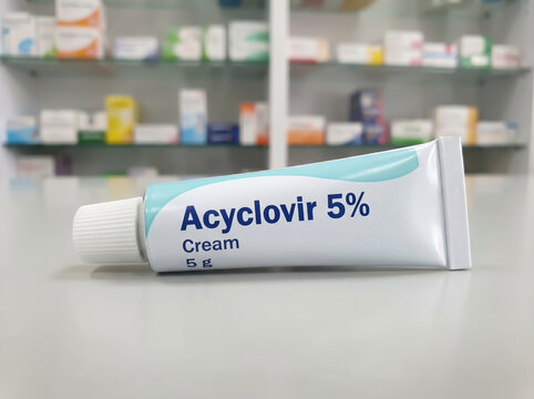 Acyclovir 5% antiviral cream tube on a pharmacy counter background
