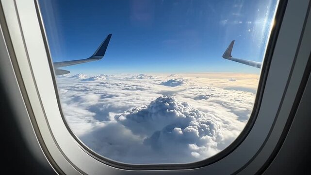 View of clouds and airplane wing through a passenger window.