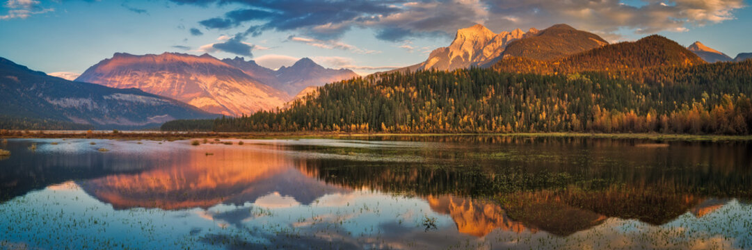 Canadian Rockies mountains reflecting in calm lake at sunset