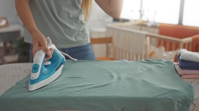 Woman ironing shirt with iron, hand pressing fabric on ironingboard in building; domestic routine calm.