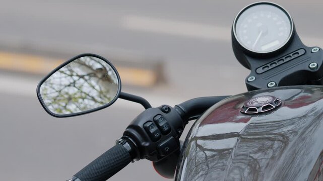 Close up shot of motorcycle handlebar and speedometer in urban setting.