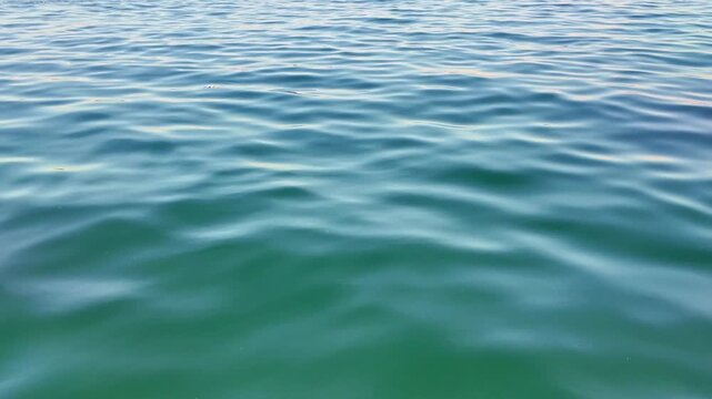 slow motion Serene ocean water surface with gentle ripples and waves. Natural water texture background of calm turquoise sea creating a tranquil and relaxing mood