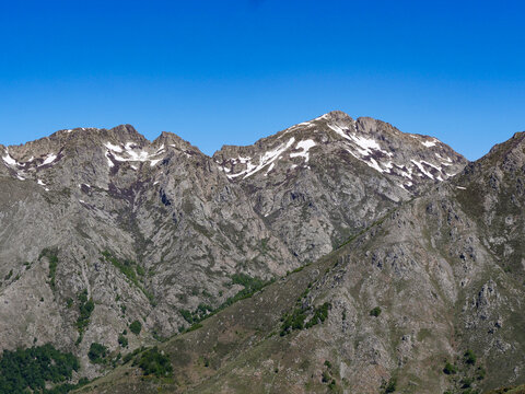 Dramatic rocky peaks with melting snow under deep blue sky at Val d'Ese Corsica