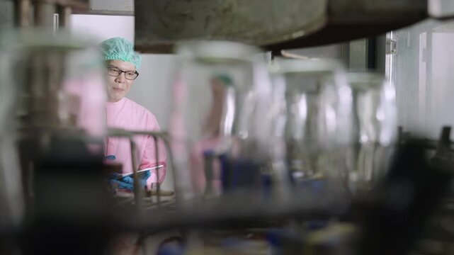 Professional Asian maintenance engineer and technician in food and beverage drink factory in uniform with tablet while talking and discussing machine operation in production line at industry facility.