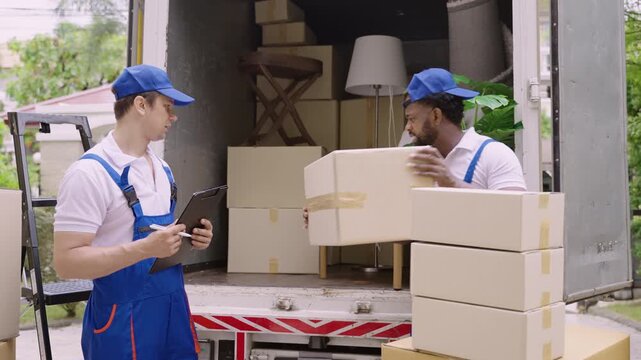 Home moving and delivery service concept. Teamwork of professional home and furniture moving with a truck from business service company. Two male movers in uniforms working and delivering to customer.