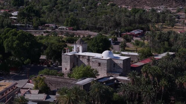 View the aerial shots of Mission Church located in San Ignacio, Baja California. This location shows the church and surrounding oasis area.