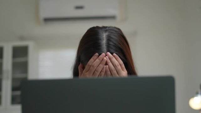 Overwhelmed young asian businesswoman feeling stressed and tired from work. Frustrated female employee crying and covering her face with hands
