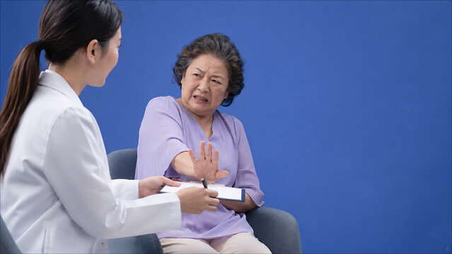 Elderly Asian woman refusing doctor consultation, anxiety and mistrust