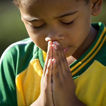 a young boy praying with his hands and fingers raised in a prayer pose