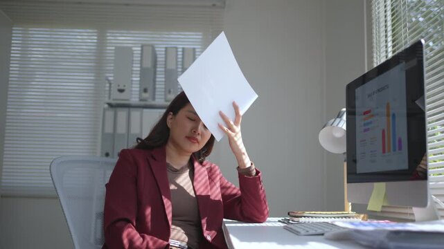 Exhausted young asian businesswoman feeling sleepy after working on a computer and reviewing documents, finally falling asleep at her desk