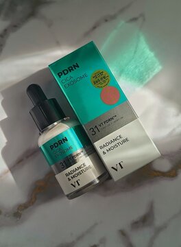 Vt cosmetics cica exosomes vegan pdrn serum ampoule bottle and box top view on light marble background in sunlight 