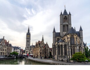 Obraz premium A serene cityscape featuring a large, historic church with a tall spire and a smaller tower in the background, overlooking a calm river
