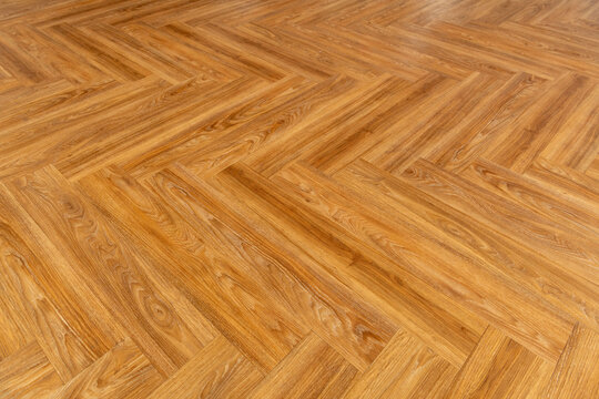 Wooden herringbone parquet flooring with a warm, natural finish.