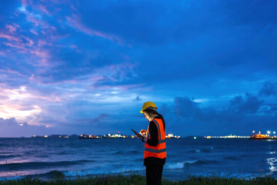 Professional Asian female engineer coordinating Energy operations near the coast, supporting Industry leadership, Oil refinery modernization, and AI-powered monitoring.
