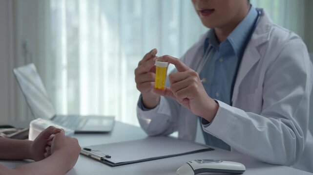 Male doctor in a white coat explaining the dosage of a medication from a yellow bottle to a patient during a consultation in his office