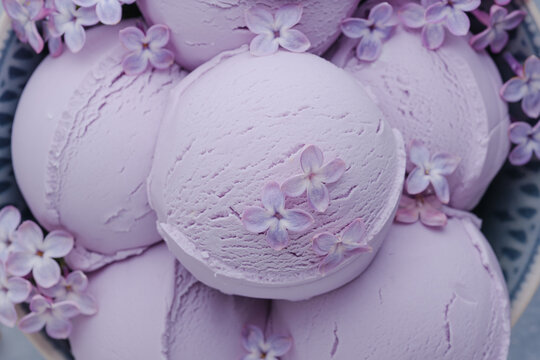 Close up of creamy lavender ice cream scoops topped with delicate lilac blossoms. Healthy frozen dessert. top view
