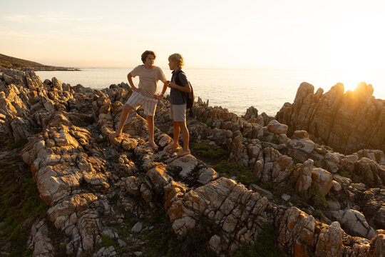 2 pre teen boys climbing and exploring rocky coastline of DeKelders, South Africa