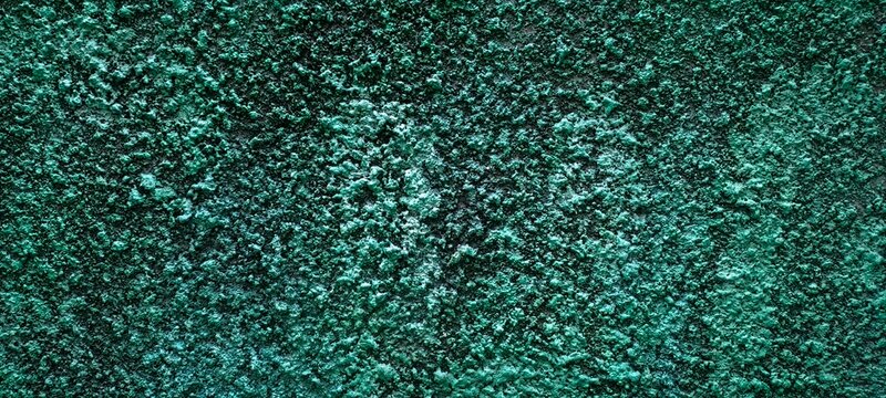 Rough emerald green textured wall background with bumpy plaster surface and dark shadows
