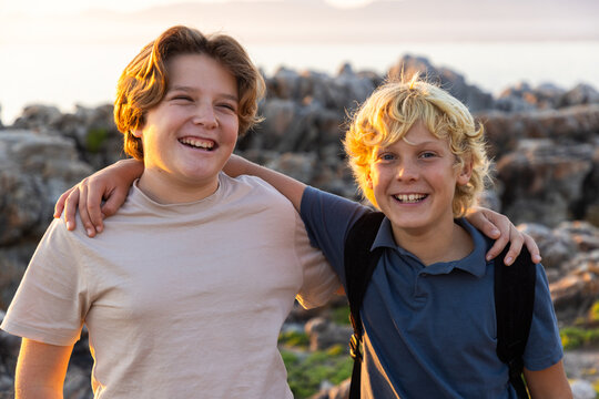 2 pre teen boys climbing and exploring rocky coastline of DeKelders, South Africa