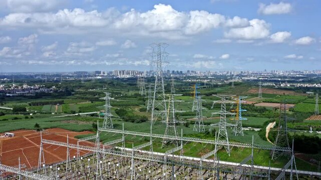 Electrical substation and transmission towers across farmland near city skyline