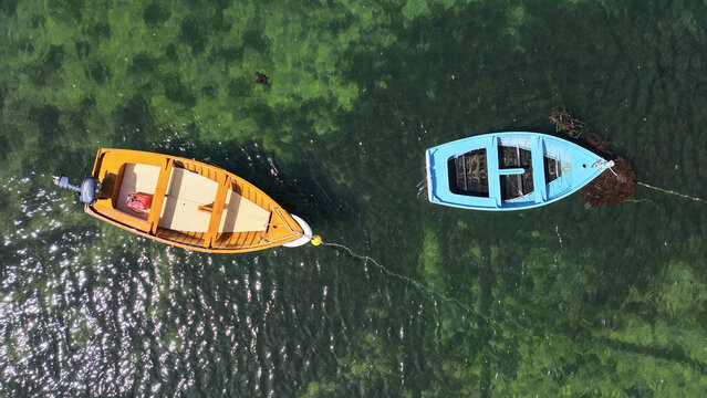 Aerial view of two small wooden boats floating on clear green water near Ile Callot in Carantec, Brittany, France.